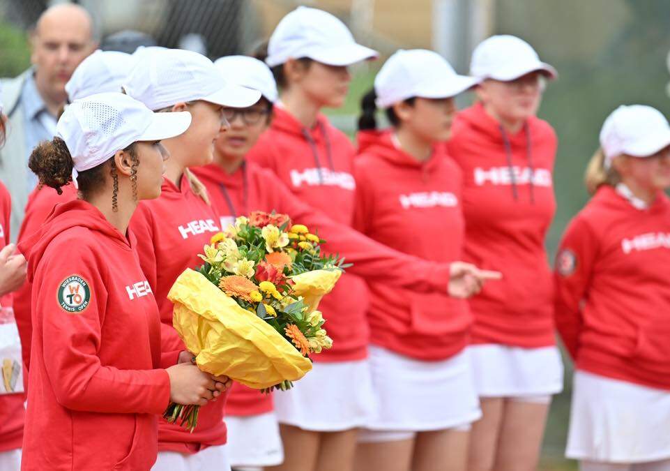 Ballkinder in roter Teamkleidung mit Blumen